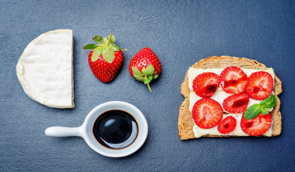 strawberry and cheese sandwhich with a separate balsamic vinegar in a small bowl
