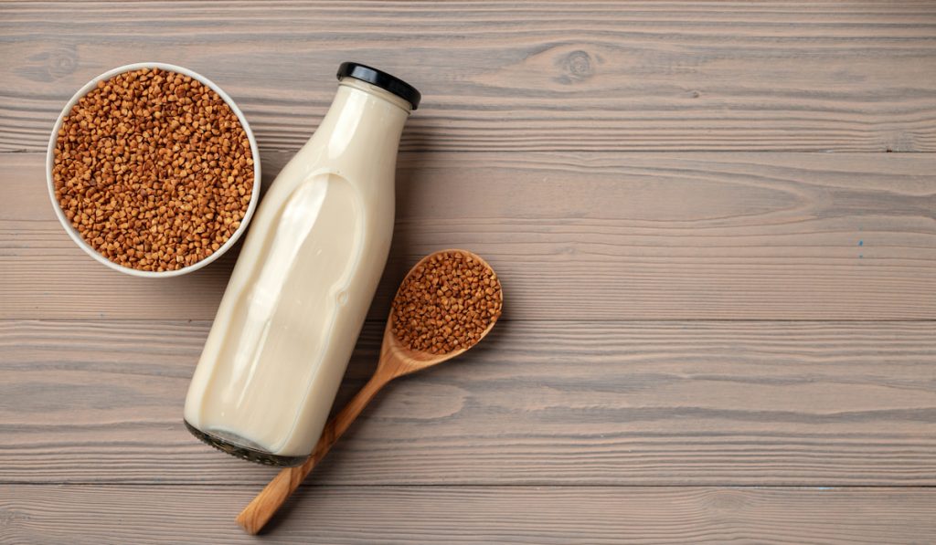 Buckwheat milk concept with bottle of milk and buckwheat grain in bowl