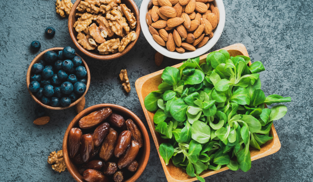 Healthy vegan food - dry fruits, greens, nuts, berry. Superfoods on gray stone background, top view.
