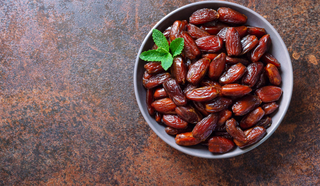 Sun-dried dates fruits in a ceramic bowl. Organic dried fruits.