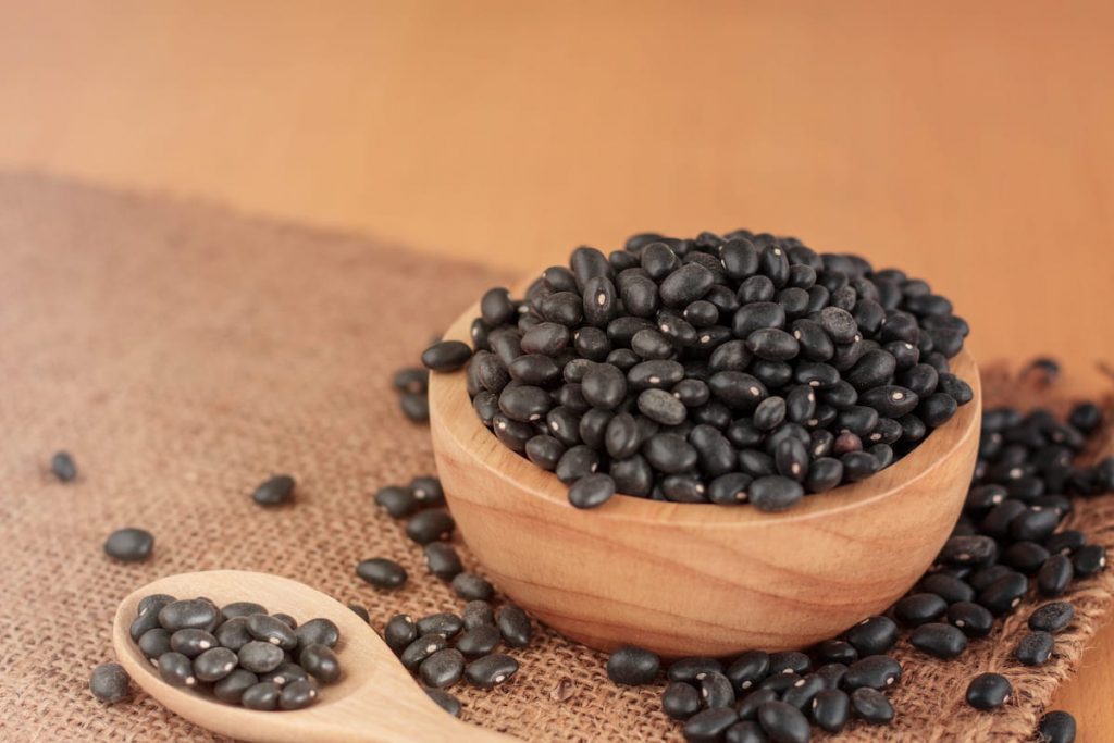 black beans on wooden saucer on wooden mat