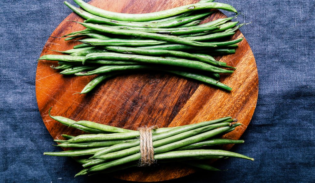 bundle of green beans on a chopping board 
