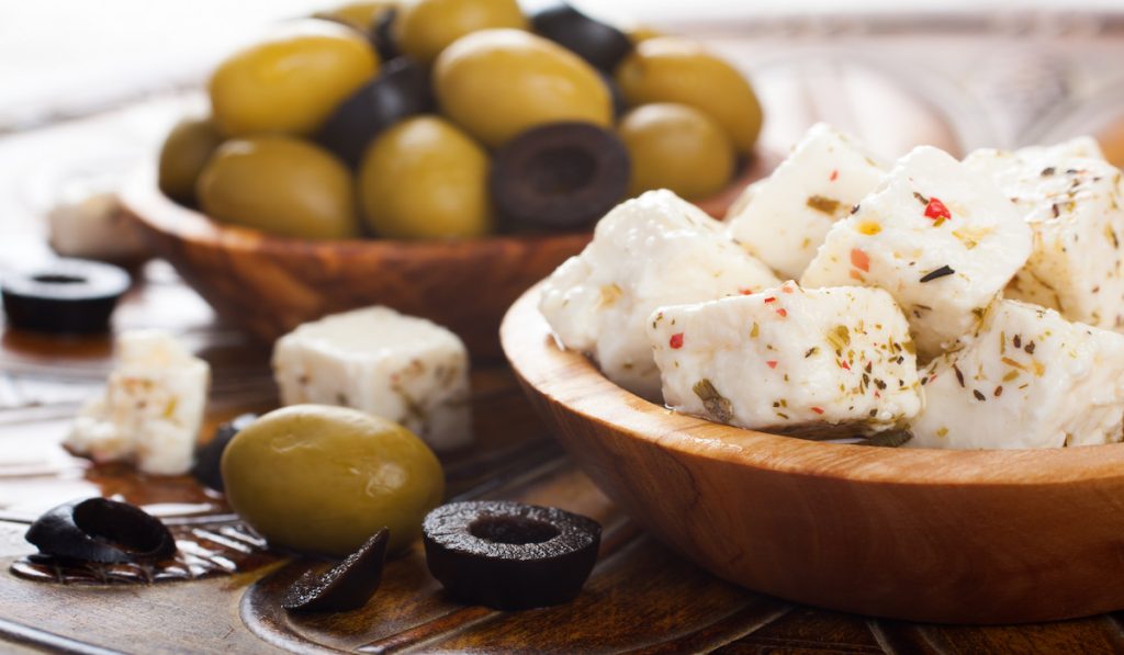 cubed feta cheese and olives in a wooden bowl