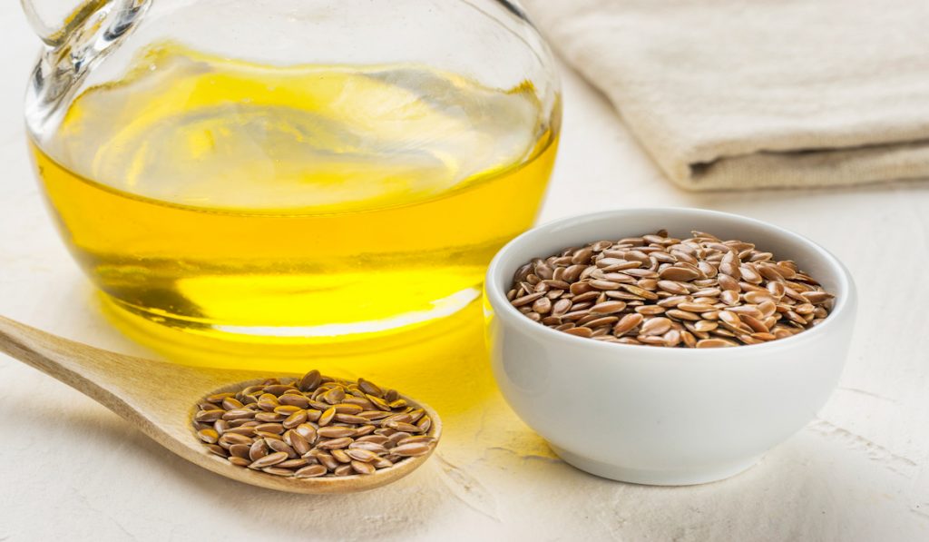 flax seeds in a spoon and bowl and flaxseed oil