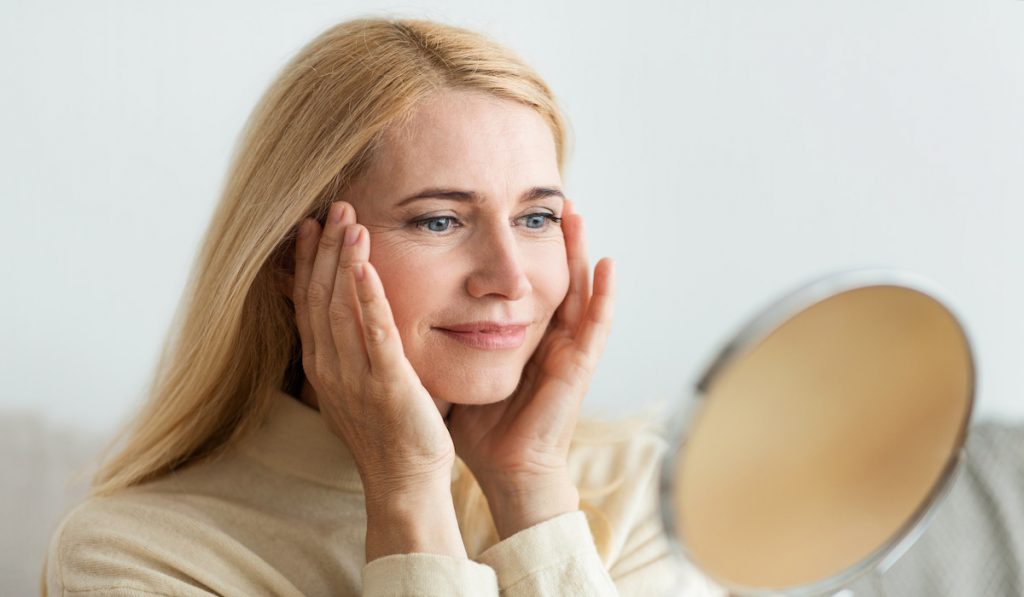 middle aged woman holding her face and checking her skin