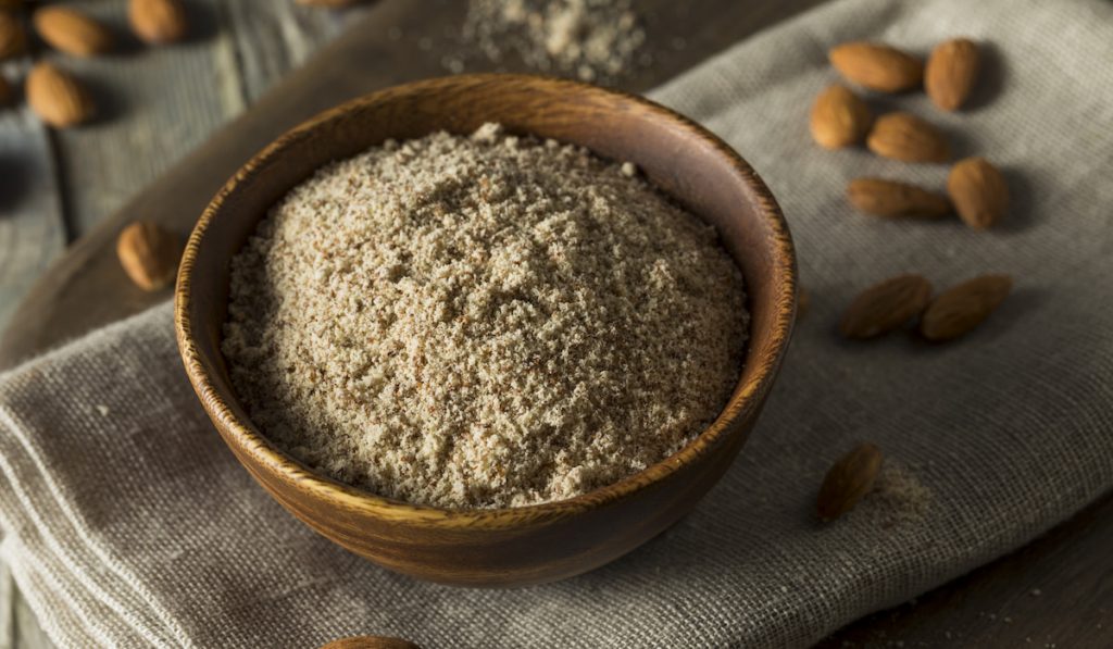 raw organic almond flour on wooden bowl