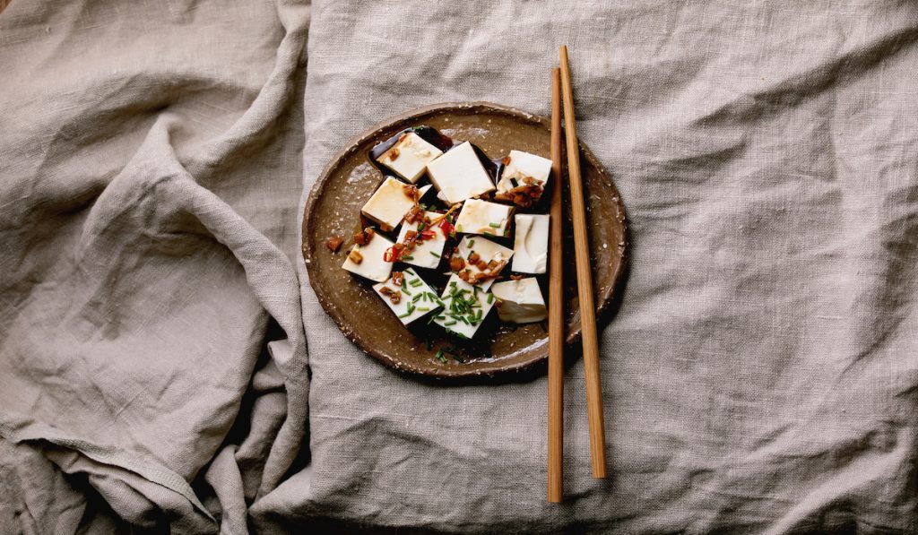 silky tofu with some herbs and soy sauce with a chopstick 