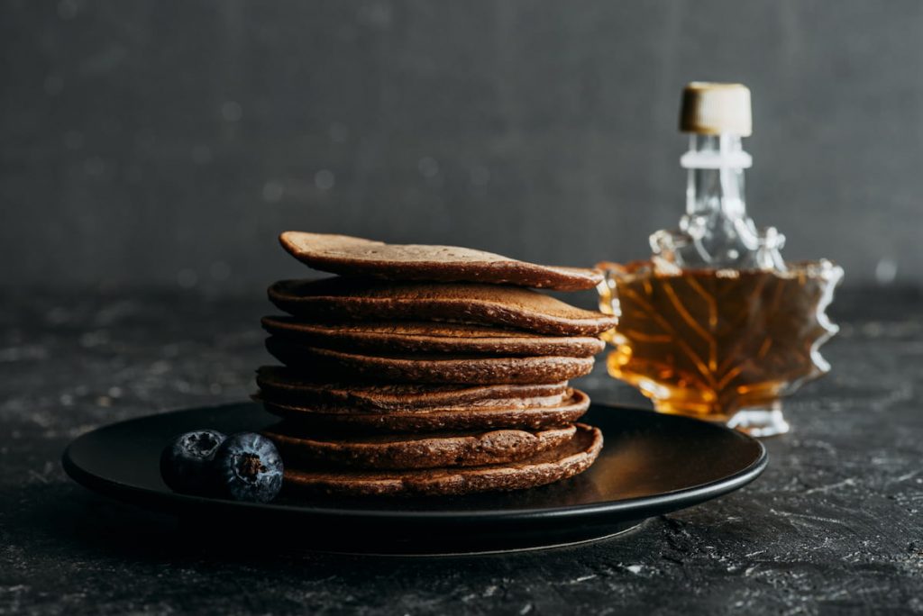 stacked pancakes with bottle of maple syrup