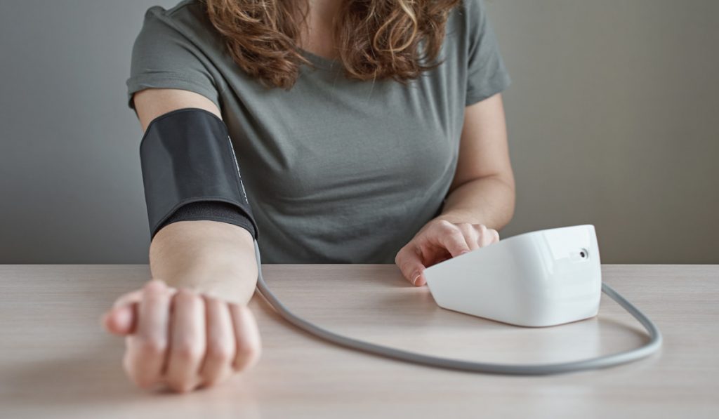 woman measuring her own blood pressure using a digital pressure gauge 