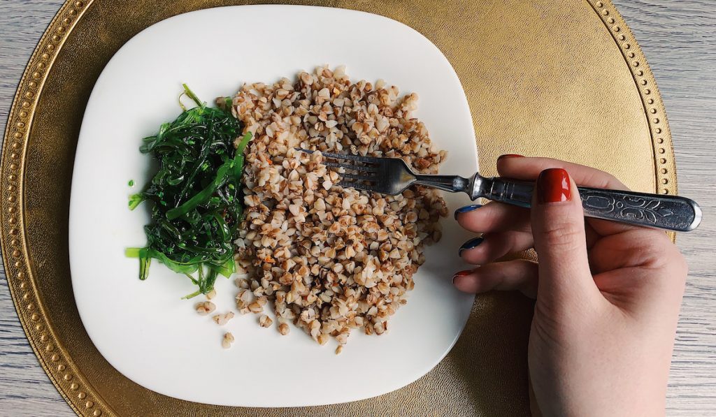 woman using fork for her Buckwheat with chuka on square plate 