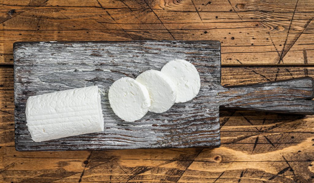 Sliced Soft Goat cheese on a cutting board.