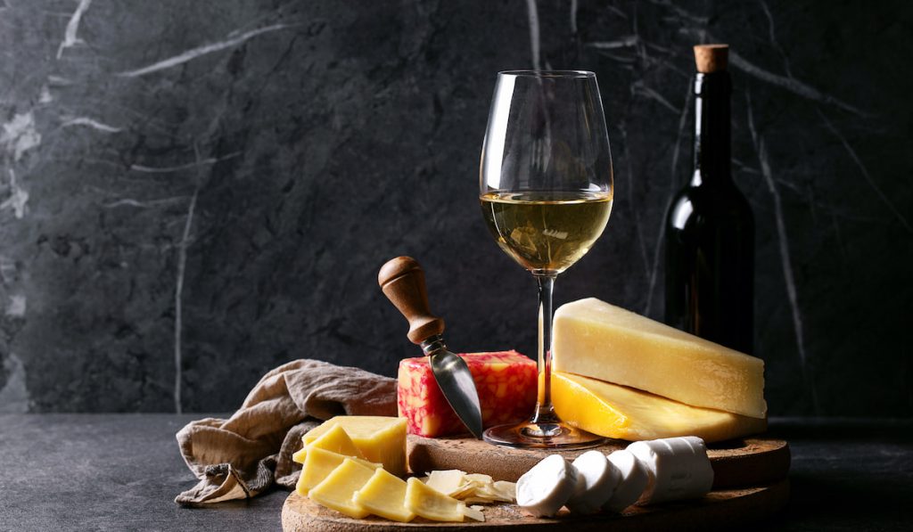 Variety of goat and cow milk cheese with wine glass and bottle